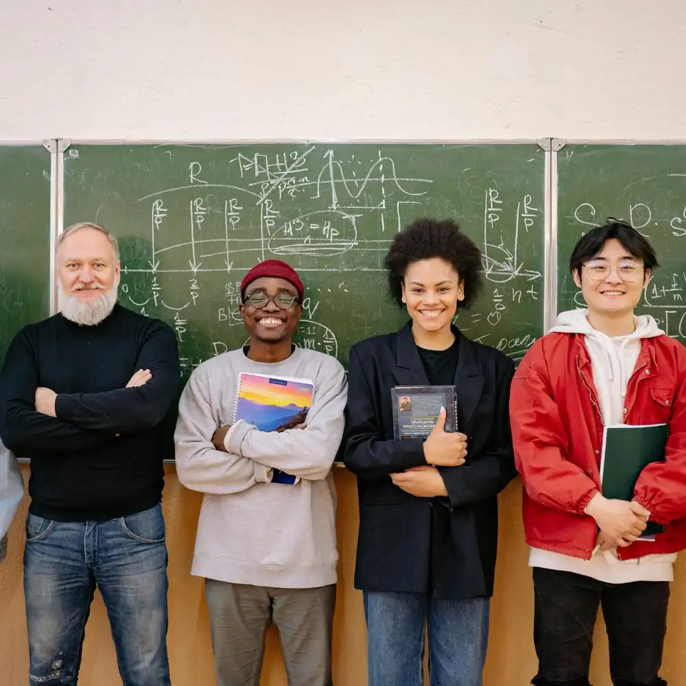 Group of diverse students and their teacher standing in front of a chalkboard with math formulas, smiling together.