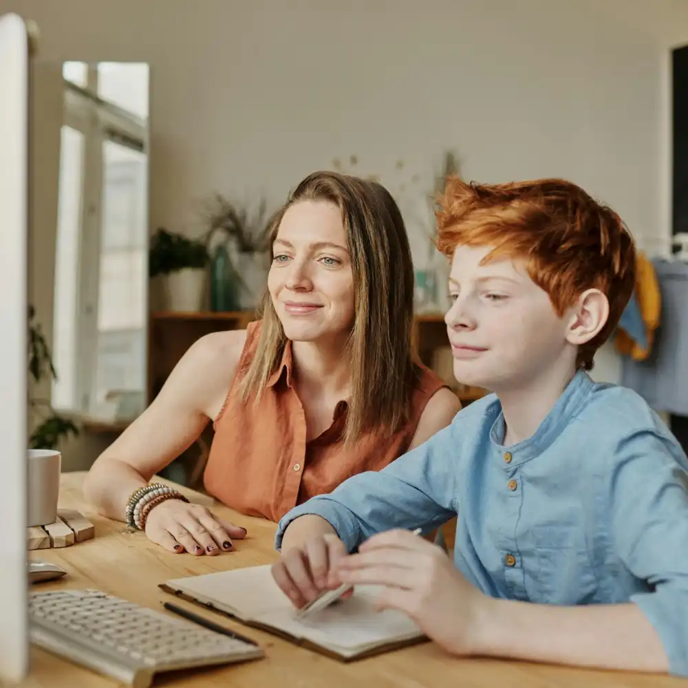 Tutor guiding a child during an online learning session using a computer at home