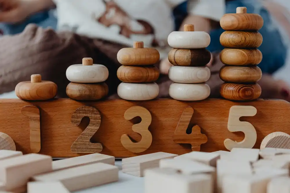 Close-up of natural wooden counting toys with stackable rings and numbers used for early learning activities.